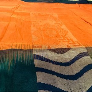 Vibrant orange pure silk saree with dark green and black border.